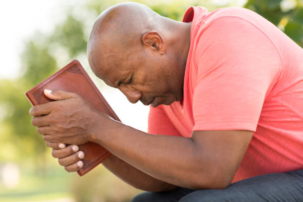 man sitting and leaning over holding Bible