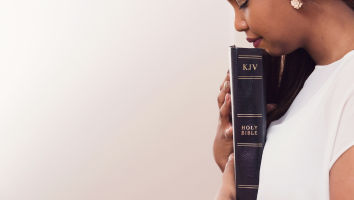 woman with eyes closed holding Bible in hands